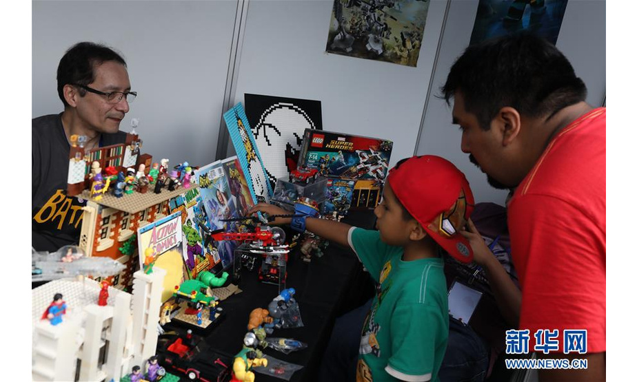 5月4日，在秘鲁首都利马，一对父子在“漫画日”活动上选购动漫玩具。  新华社发 （玛利亚娜·巴索摄）