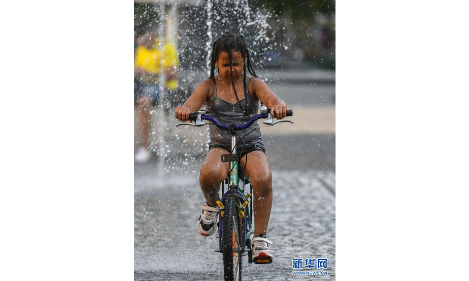 6月17日，在德国法兰克福，一名小朋友骑车穿过喷泉纳凉。

　　当日，法兰克福遭遇高温天气，最高气温达36摄氏度。

　　新华社记者逯阳摄