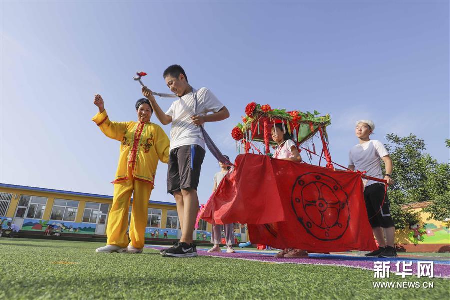 8月4日，民间艺人在河北省遵化市平安城镇大麻各庄村校园操场指导孩子们学习民俗节目。新华社发（刘满仓 摄）