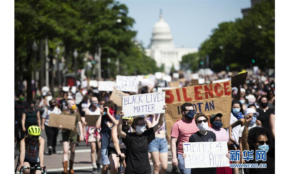5月30日，在美国首都华盛顿国会山附近，人们手持标语参加抗议活动。 新华社记者 刘杰 摄