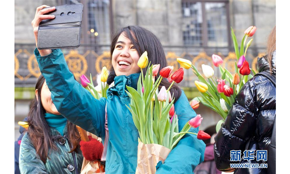 1月18日，在荷兰阿姆斯特丹，一名参与者在水坝广场捧着郁金香自拍。 当日，荷兰迎来一年一度的国家郁金香日。 新华社发（西尔维娅·莱德雷尔摄）