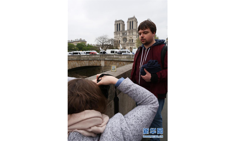 4月16日，在法国巴黎，一对情侣为巴黎圣母院和它的小画像拍合影。新华社记者 高静 摄