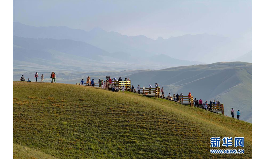 游客在喀拉峻草原上游玩（8月13日摄）。 喀拉峻草原位于新疆伊犁河谷的特克斯县境内，山峦连绵起伏，线条柔美，层次分明，犹如一幅大气磅礴的天然画卷。 新华社记者 胡虎虎 摄