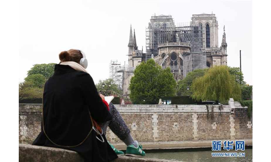 4月16日，在法国巴黎，一名女子在塞纳河畔为“受伤”的巴黎圣母院写生。新华社记者 高静 摄