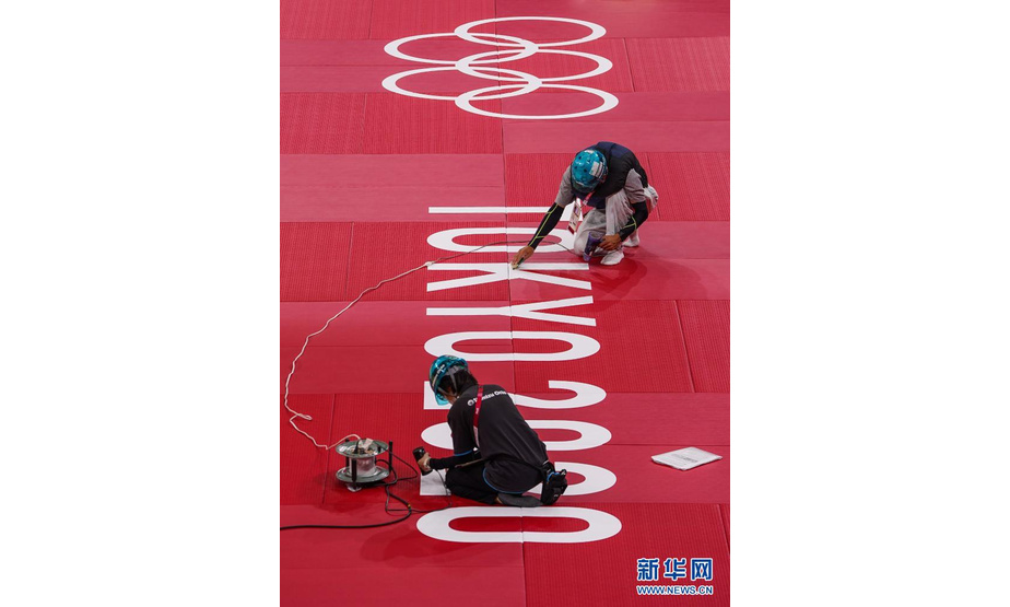 7月21日，日本武道馆内的奥运会工作人员在柔道比赛台垫上张贴奥运标识。

　　东京奥运会开赛在即，各项目比赛场馆准备工作有序进行。

　　新华社记者 刘大伟 摄