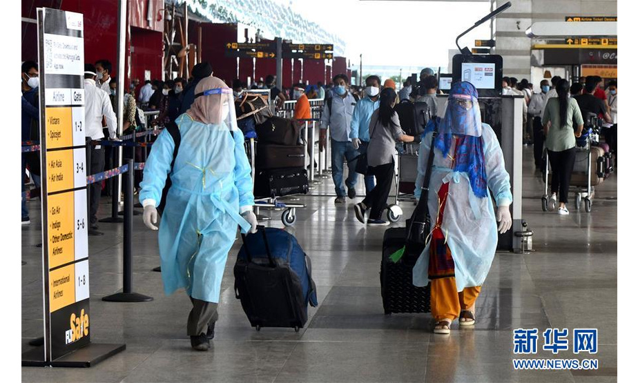 5月25日，在印度新德里英迪拉·甘地国际机场，两名旅客穿戴着防护服和面罩出行。 印度政府允许国内航线自5月25日起恢复。 新华社发（帕塔·萨卡尔摄）