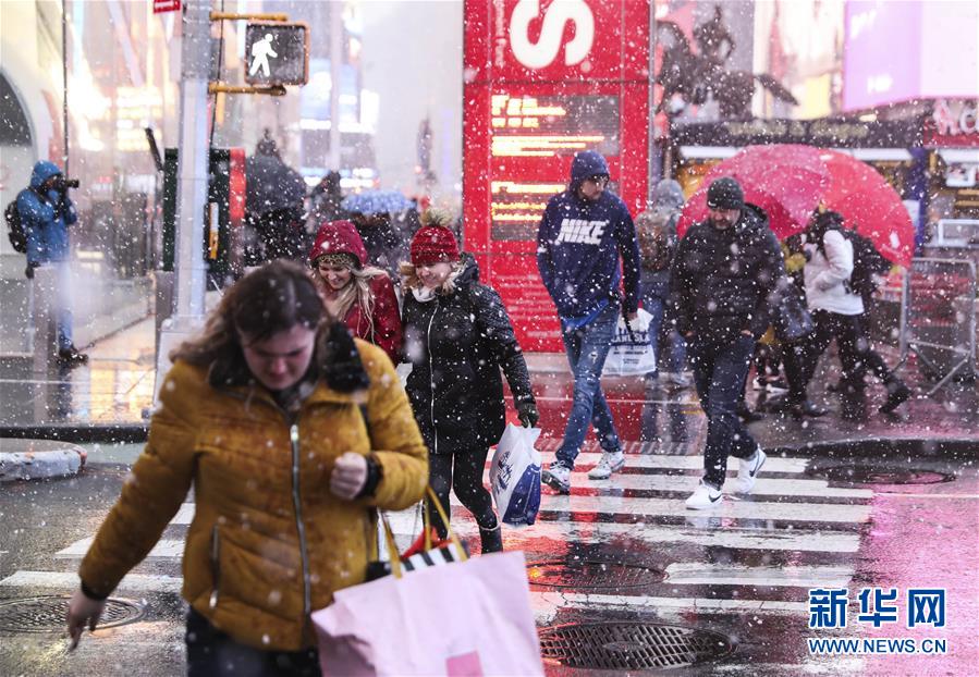 12月2日，行人冒雪走在美国纽约时报广场上。 当天，纽约遭遇雨雪天气，给人们出行带来不便。 新华社记者 王迎 摄