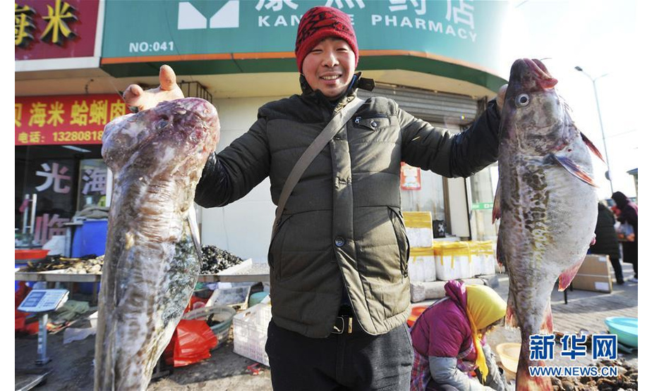 1月15日，商户在山东青岛沙子口年货大集上向顾客展示鱼类。

　　春节临近，各地商贸、年货集市日渐火爆，年味越来越浓。

　　新华社发（王海滨 摄）