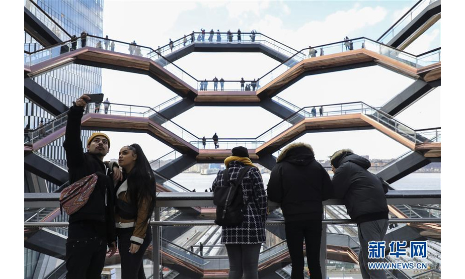 3月18日，人们在美国纽约曼哈顿哈得孙河畔名为“Vessel”的景观建筑上观赏风景。 这座蜂窝式结构的建筑由154段楼梯、80个楼梯平台组成，供参观者从不同角度观赏城市风光。该景观3月15日正式向公众开放，每日的参观者络绎不绝。 新华社记者 王迎 摄
