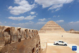 这是9月14日在埃及首都开罗以南的塞加拉地区一座左塞尔时期古墓的地上建筑拍摄的眼镜蛇雕像，以及远处的阶梯金字塔。<br/><br/>　　当日，位于埃及首都开罗以南约30公里的塞加拉地区，一座距今4000多年的古埃及第三王朝国王左塞尔时期的古墓经过近15年的修缮后正式向公众开放。该墓位于左塞尔王阶梯金字塔建筑群西南角，由地上建筑和地下墓室两大部分构成。埃及于2006年启动对该墓墓道、墓墙、墓室等建筑体的保护和修缮工作。<br/><br/>　　新华社记者 隋先凯 摄