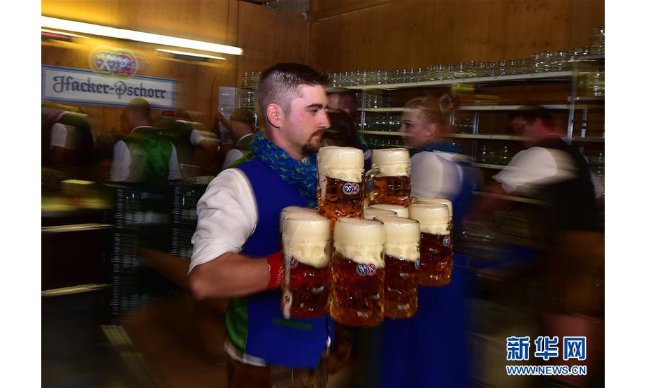 9月21日，在德国慕尼黑啤酒节上，一名工作人员为顾客送啤酒。 当日，第186届慕尼黑啤酒节在德国南部城市慕尼黑开幕。作为德国最大的民间盛事，本届啤酒节将持续至10月6日。 新华社记者 逯阳 摄