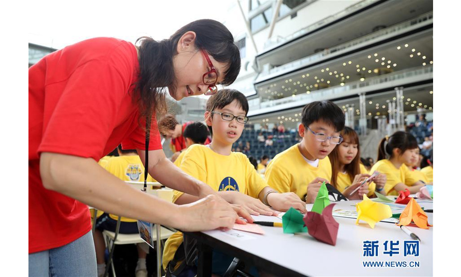 4月19日，工作人员在活动现场指导学生折纸。 当日，香港多所中小学和社会团体的上千名成员参加一场名为“同心创世界纪录”的活动，在一名折纸艺术家带领下刷新“最大规模折纸课”的吉尼斯世界纪录。新华社记者 吴晓初 摄