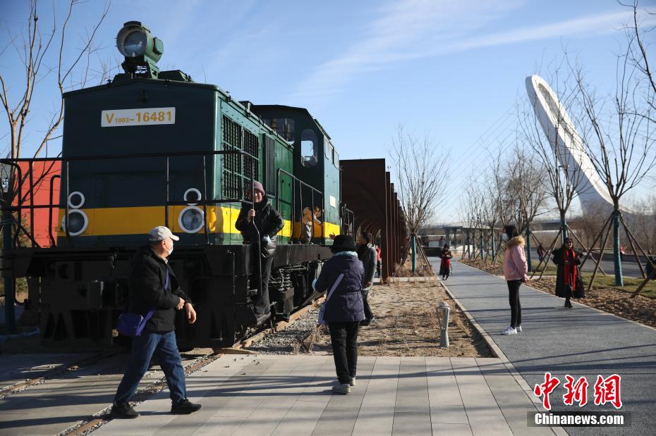 12月1日，民众在冬奥公园火车乐园景观前游玩。近日，北京冬奥公园永定河左岸公共空间提升工程全部完工。丰沙记忆、织梦奥运、生活聚场、冰雪童趣四个主题景观节点开放亮相，突出“冬奥后花园”冰雪特色，为民众提供更加优美的滨水活动休闲场所。 中新社记者 赵隽 摄