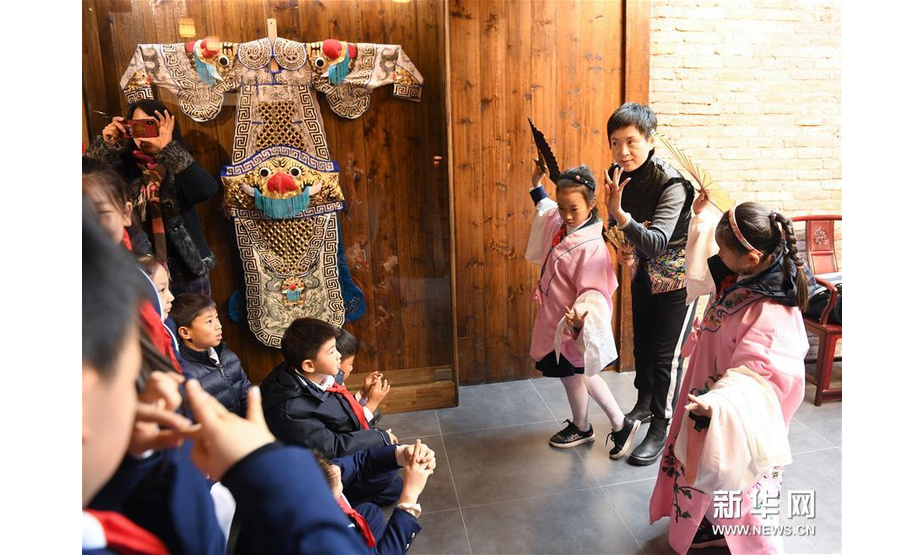 12月11日，杨崑（右二）为前来研学的小学生讲解昆曲，并让两名学生穿上戏服体验昆曲表演。新华社记者翁忻旸摄