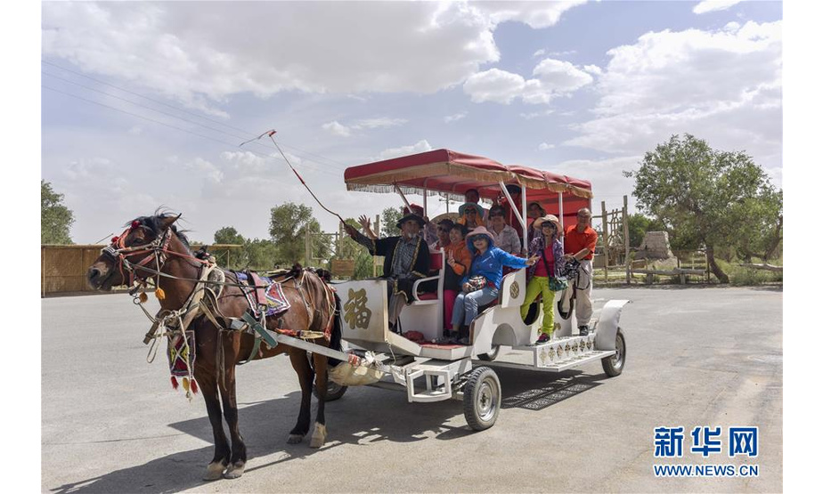游客乘坐马车在罗布人村寨里游览（6月19日摄）。 入夏以来，新疆尉犁县罗布人村寨景区迎来旅游旺季。根据景区提供的数据，自“五一”小长假至6月23日，罗布人村寨接待游客5.2万多人次，相比去年同期增长约78%。 新华社记者 赵戈 摄