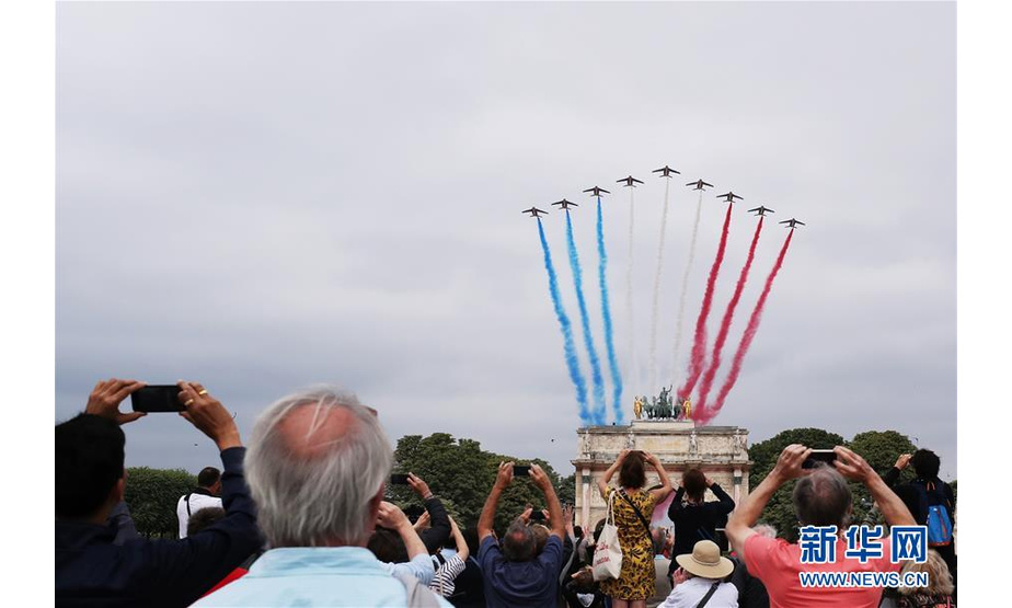 7月14日，在法国巴黎举行的国庆阅兵仪式上，“法兰西巡逻兵”飞行表演队飞过卢浮宫金字塔广场附近的小凯旋门上空。 当日，法国在首都巴黎举行国庆阅兵仪式。 新华社记者 高静 摄