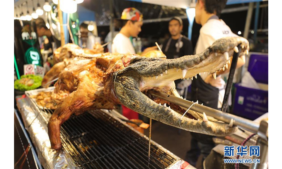 8月10日，在泰国曼谷河滨夜市，商贩在售卖烤鳄鱼。 夜幕之下，多姿多彩的夜生活让曼谷这座城市充满活力。 新华社记者 张可任 摄