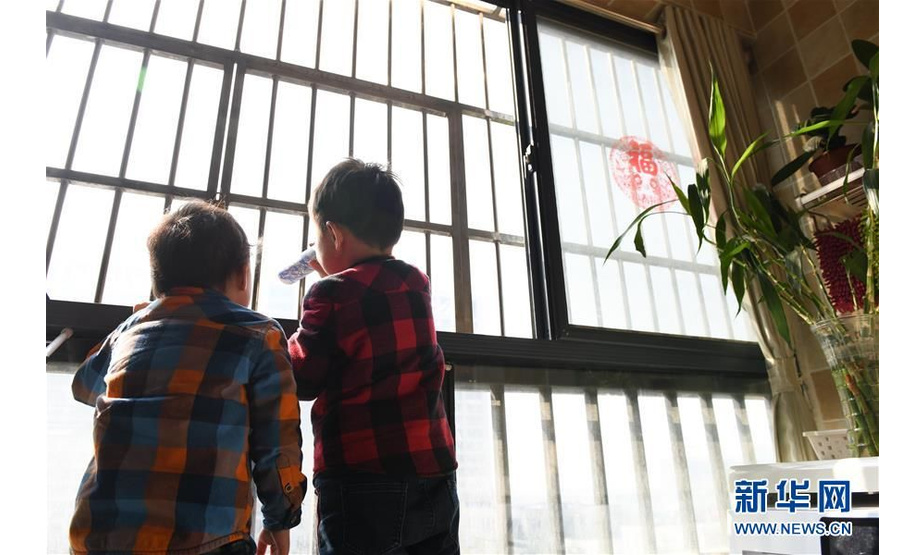合肥第二人民医院附近，儿子在家中阳台手持自制“放大镜”，眺望在对面医院“打病毒”的护士妈妈（2月3日摄）。新华社记者 张端 摄