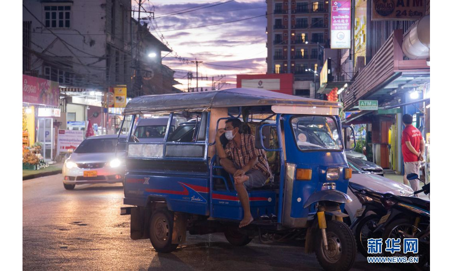 7月21日，一名三轮摩托车驾驶员在老挝首都万象湄公河边夜市等候客人。

　　由于从邻国输入的新冠确诊病例不断增加，老挝政府19日宣布再次延长疫情防控期15天至8月3日。

　　新华社发（凯乔摄）