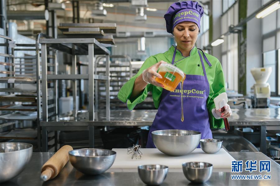 8月28日，在俄罗斯首都莫斯科，糕点师尤利娅将俄式蜂蜜蛋糕的“灵魂”——蜂蜜倒入碗中。新华社发（叶甫盖尼·西尼岑摄）