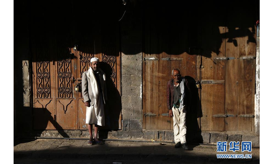 12月17日，在也门首都萨那，两名男子站在路旁。也门政府17日晚发布命令，要求政府军自18日起在荷台达实施停火。新华社发（穆罕默德摄）