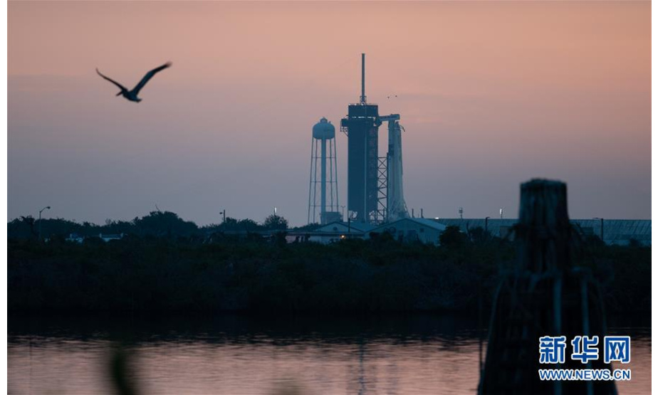 美国航天局原定于5月27日用载人版“龙”飞船将两名美国宇航员送往国际空间站，但因天气原因推迟。下一次发射窗口为美国东部时间30日15时22分（北京时间31日3时22分）。 这是5月27日在美国佛罗里达州肯尼迪航天中心拍摄的“猎鹰9”火箭和载人版“龙”飞船。 新华社发（美国国家航空航天局供图）