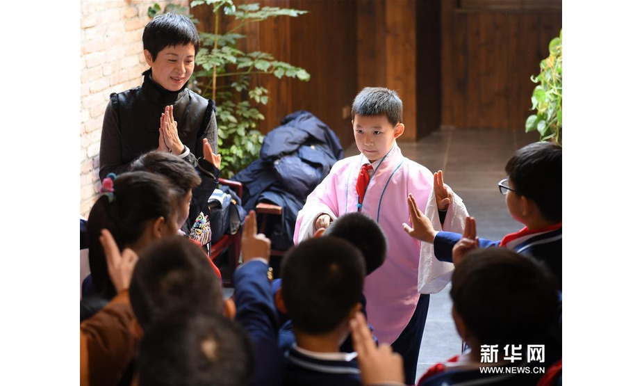 12月11日，杨崑（上左）在“小河驿国际昆曲会客厅”为前来研学的小学生讲解昆曲表演。新华社记者翁忻旸摄