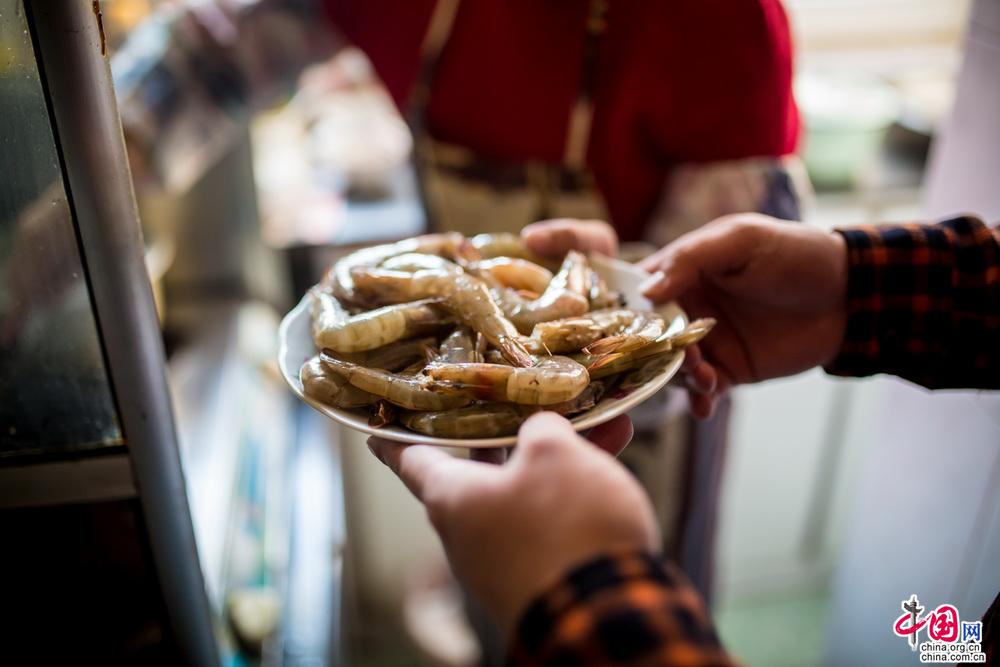 接过递上的大虾准备下锅，看到妈妈似乎又有些许消瘦的手，心里泛起涟漪，这一双手把我带大，拉着儿时的我走遍各处……现在自己长大了，妈妈也老了，也很久不曾再拉着妈妈的手了，今年，妈妈从返聘的岗位上彻底退休了，也许该我牵着妈妈的手，带她出去走走了。中国网记者 郑亮 摄