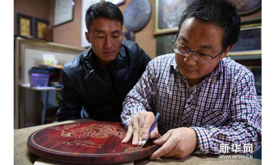 5月6日，申洪杰（右）在敦煌市沙州市场的工作室内教徒弟雕刻敦煌木刻画。 新华社记者范培珅摄 