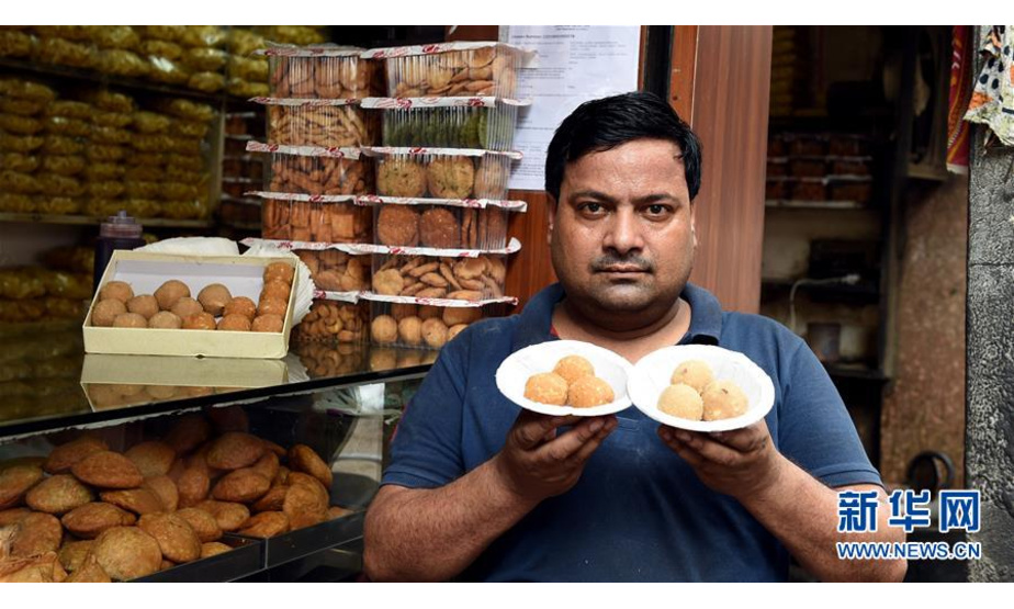 8月27日，在印度首都新德里一家甜品店，一名男子展示传统甜点“拉杜”。 新华社记者 张迺杰 摄