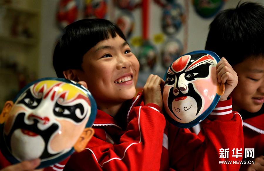 4月12日，在张智家中，一名小学生在体验脸谱制作技艺。 新华社发（陈其保 摄）