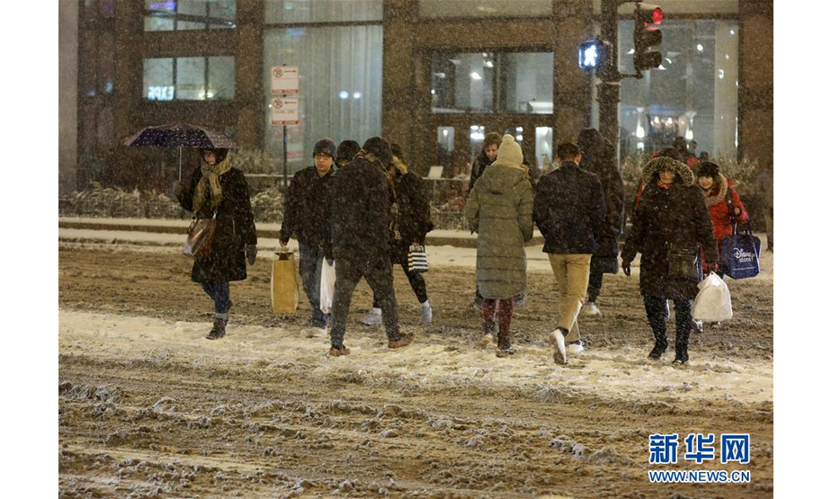 1月17日，在美国芝加哥，行人冒雪出行。 美国芝加哥当日遭暴风雪袭击，地面积雪严重，影响交通和出行。 新华社记者 汪平 摄