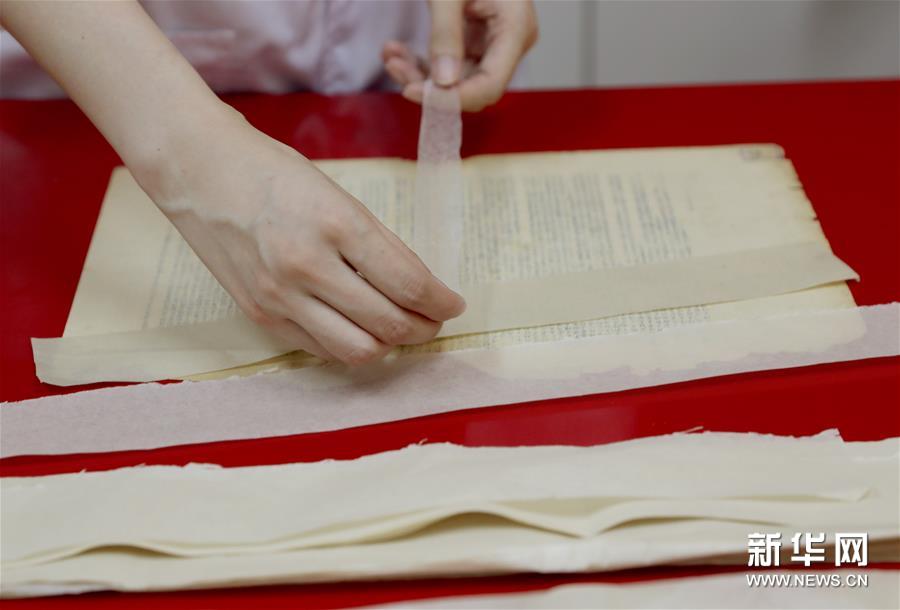 6月29日，上海市档案馆保护技术部的工作人员在选择档案修复用纸的材质和色号，从而确定修复方案。新华社记者 刘颖 摄