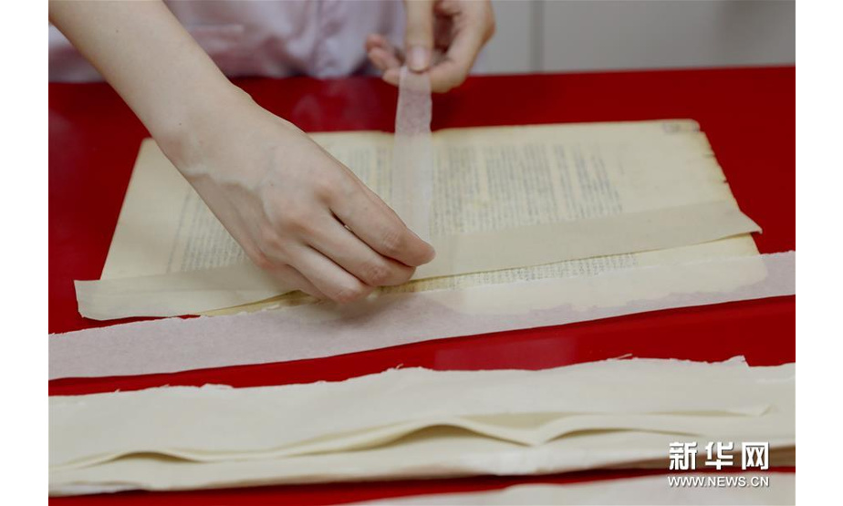 6月29日，上海市档案馆保护技术部的工作人员在选择档案修复用纸的材质和色号，从而确定修复方案。新华社记者 刘颖 摄