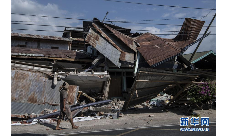 8月8日，在印度尼西亚龙目岛地震灾区，一名男子走过倒塌的房屋。 新华社记者吕小炜摄