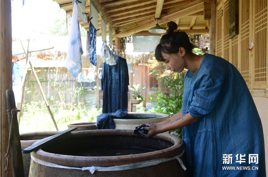 6月30日，陈燃在染坊中制作染料。1994年出生的四川姑娘陈燃大学毕业后迷上了蓝染工艺，并前往贵州丹寨山村的古法染坊向当地的手艺人学习。2017年，陈燃在丈夫的老家安徽黟县建立了自己的蓝染工坊。 蓝染是一种古老的印染工艺，用蓝染植物发酵后制作成染液，通过绑扎、浸泡、氧化和晾晒，让布料拥有独一无二的蓝色。“学习蓝染需要很大的耐心，要学会‘养缸’，不断调整染料的配比，染缸的状态决定了成品的效果。”陈燃说。经过无数次对染料成分和布料的试验，陈燃熟练掌握了传统的蓝染技艺，并继续探索创新。 2018年，陈燃应顾客要求定制蓝染产品，从衣服逐渐扩展到门帘、床单、抱枕、餐垫等家居用品。在设计方面，在保留传统特色的同时，陈燃对传统图案和样式进行了改良，更加注重产品的实用性、简约性。 染坊成立三年多以来，陈燃坚持开设蓝染体验课程，为游客示范、讲解蓝染技艺，接待游客超过十万人次。“我希望通过自己的努力能让更多的年轻人了解蓝染，让‘一抹蓝’走进更多人的生活。”陈燃说。新华社记者 韩晓雨 摄


