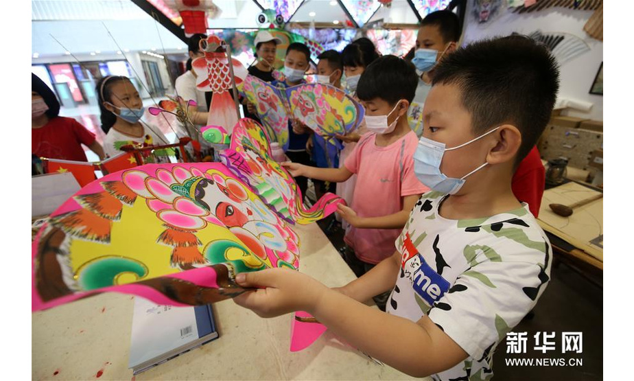 7月8日，山东省潍坊市潍城区城关街道十笏园社区的小朋友在了解潍坊风筝的制作工艺。新华社发（张驰 摄）