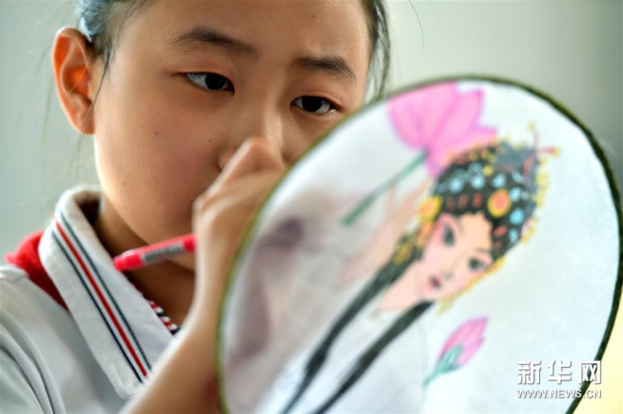6月11日，在石家庄市青少年宫，裕华西路小学的学生在扇面上画戏曲人物。 当日，河北省石家庄市裕华西路小学举办“弘扬戏曲艺术 传承经典国粹”为主题的校园戏曲节活动，学生通过演绎经典戏曲选段、戏曲文化社团展示等形式，呈现戏曲特色课程的学习成果。 新华社发（张晓峰 摄）