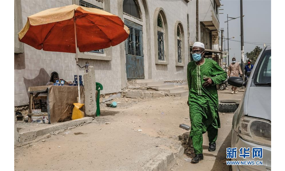 6月3日，塞内加尔首都达喀尔街头的行人戴着口罩。 新华社发（埃迪·彼得斯摄）