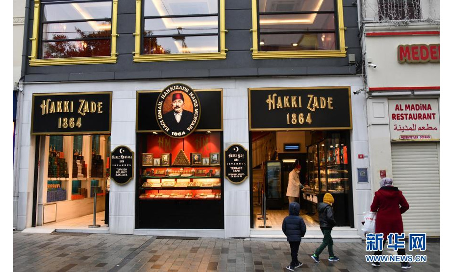 2月25日，在土耳其伊斯坦布尔的商业步行街，行人经过一家销售土耳其传统糕点的商店。

　　土耳其国家统计局日前公布的数据显示，受新冠疫情影响，土耳其2020年旅游收入约为120亿美元，较上年减少近三分之二。

　　新华社记者 徐速绘 摄