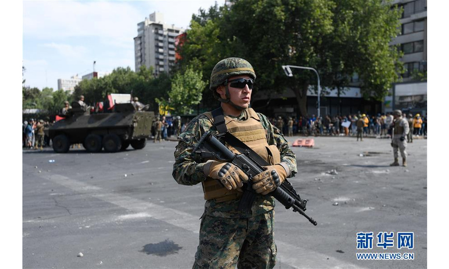 10月19日，在智利圣地亚哥，军方在街头警戒。 智利军方19日晚宣布在首都圣地亚哥实施宵禁，以避免因公交系统涨价引发的暴力抗议进一步升级。智利内政部长安德烈斯·查德威克20日说，首都圣地亚哥以外城市也出现了暴力破坏行为，康塞普西翁和瓦尔帕莱索市已进入紧急状态，他表示已经采取并将继续采取措施以保障社会秩序和公民安全。 新华社发（豪尔赫·比列加斯摄）