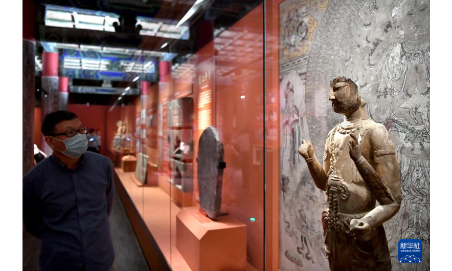 9月17日，一名参观者在展览的“丝路重华”单元参观敦煌研究院藏木雕八臂观音残像。