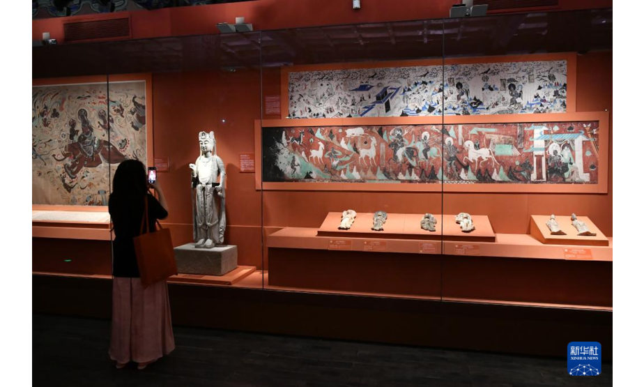 9月17日，一名参观者在展览的“丝路重华”单元拍摄甘肃省博物馆藏石雕观音菩萨立像。