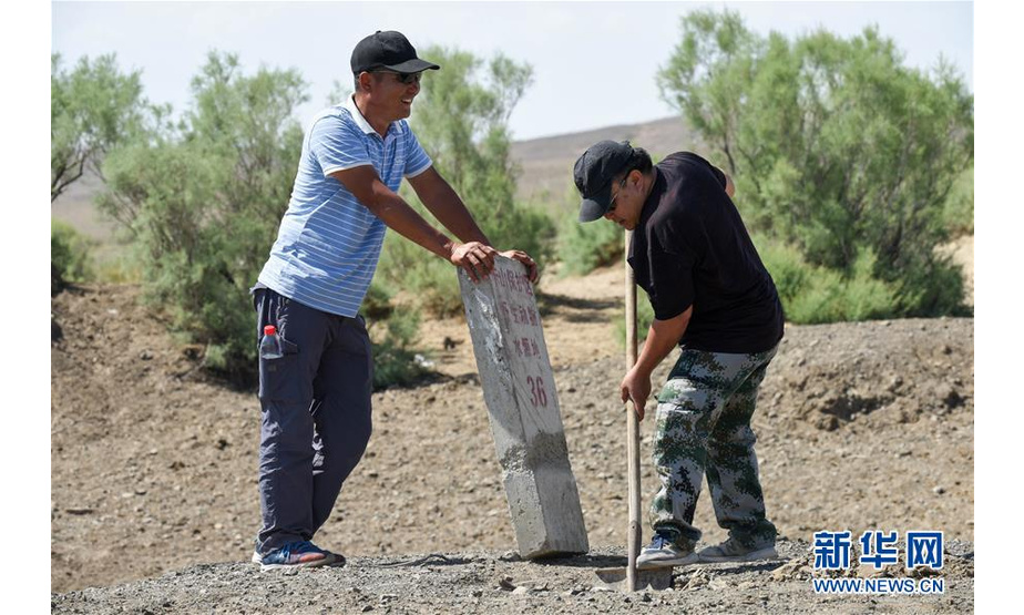 阿达比亚特（左）和同事将野生动物碰倒的水源地碑重新立好（6月3日摄）。新华社记者 丁磊 摄