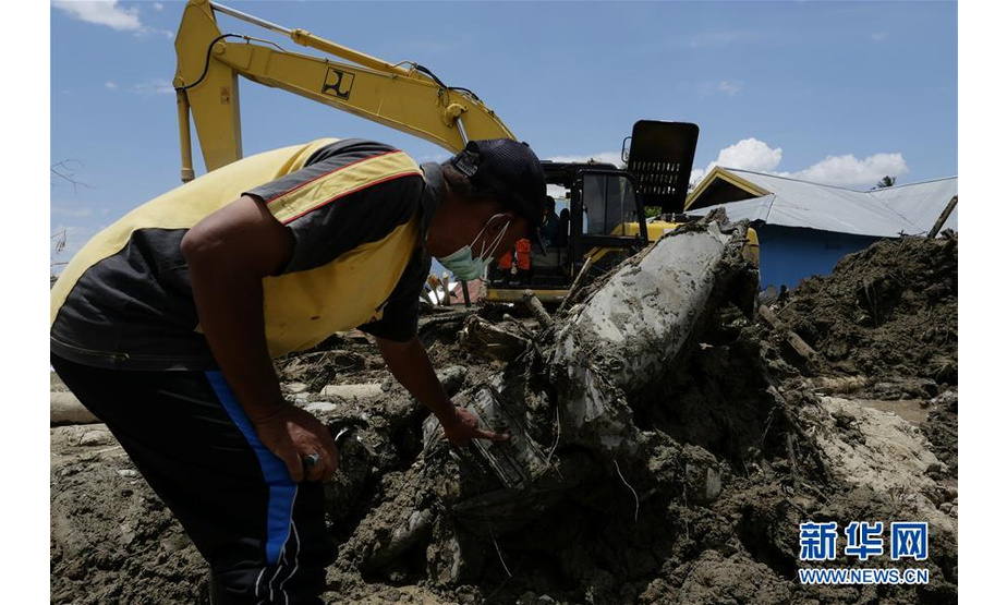 10月10日，在印度尼西亚中苏拉威西省帕卢市希吉县，村民查看从地震废墟中挖出的摩托车。 当日，印尼抗灾署发言人苏托波称，中苏拉威西省9月28日发生的强烈地震及海啸已造成2045人死亡。 新华社发（王申 摄）