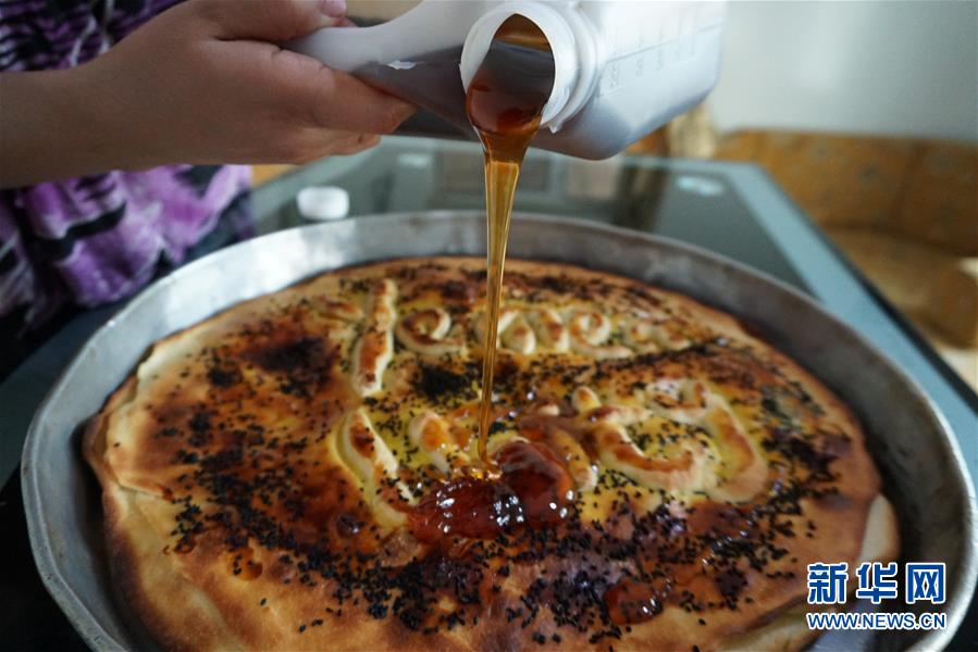 9月4日，在也门萨那，厨师在烤好的甜点“盘中少女”上倒蜂蜜。也门传统甜点“盘中少女”（一种酥皮甜饼）起源于首都萨那，是也门最著名的甜点。作为也门传统饮食文化的一部分，“盘中少女”是也门订婚和婚礼仪式中必不可少的食品，在也门北部地区格外受当地人喜爱。 制作“盘中少女”的食材主要有面粉、鸡蛋、黄油、盐、糖、蜂蜜等。先将鸡蛋、酵母、水、盐、糖加入面粉中，和成面团后醒发一小时。在面团上涂抹黄油并放置10分钟，之后将面团分成小份并揉成球状，重新醒发半小时。将面团擀成饼状后一层层放入盘中，并在层层之间刷上黄油，最顶部刷上黄油与蛋液的混合液，最后撒上香料，放置烤炉中烤至饼皮呈金黄色。取出后倒上蜂蜜，静置片刻便可趁热食用。新华社发（阿扎基摄）