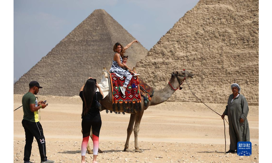 9月27日，游客在埃及吉萨金字塔群景区内骑骆驼拍照。

　　每年的9月27日是世界旅游日。新冠疫情导致埃及旅游业受到冲击，游客数量下降明显。但随着埃及国内新冠疫苗的持续接种，各类防疫措施的执行以及旅游资源的宣介和推广，埃及游客数量近来逐渐增多。吉萨金字塔群游客数量现已恢复至疫情前游客数量的一半以上。

　　新华社发（艾哈迈德·戈马摄）