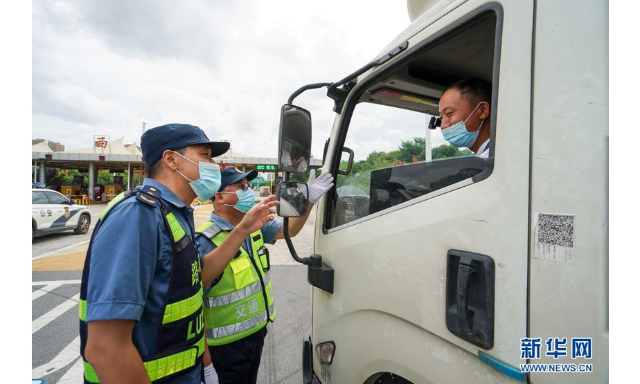 7月25日，在南京绕城高速公路西善桥收费站，执法人员向过路司机介绍疫情防控通告。新华社记者 李博 摄