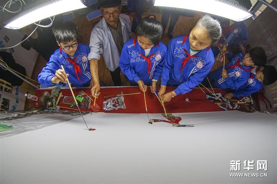 6月13日，民间艺人在大漫港小学辅导学生表演皮影戏。新华社发（刘满仓 摄）