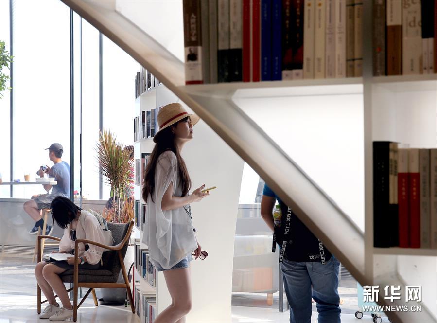 8月12日，顾客在朵云书院内参观选购。 当日，位于上海中心大厦52层的朵云书院正式开业。在离地239米的空中、2000多平方米的空间内，朵云书院售卖16000多种、6万多册中外书籍。书店集阅读、艺术展览、品牌文创、社交休闲等多功能于一体，拥有独特的空中视野和“抬头看云、低头看书”的阅读环境。 新华社记者 刘颖 摄